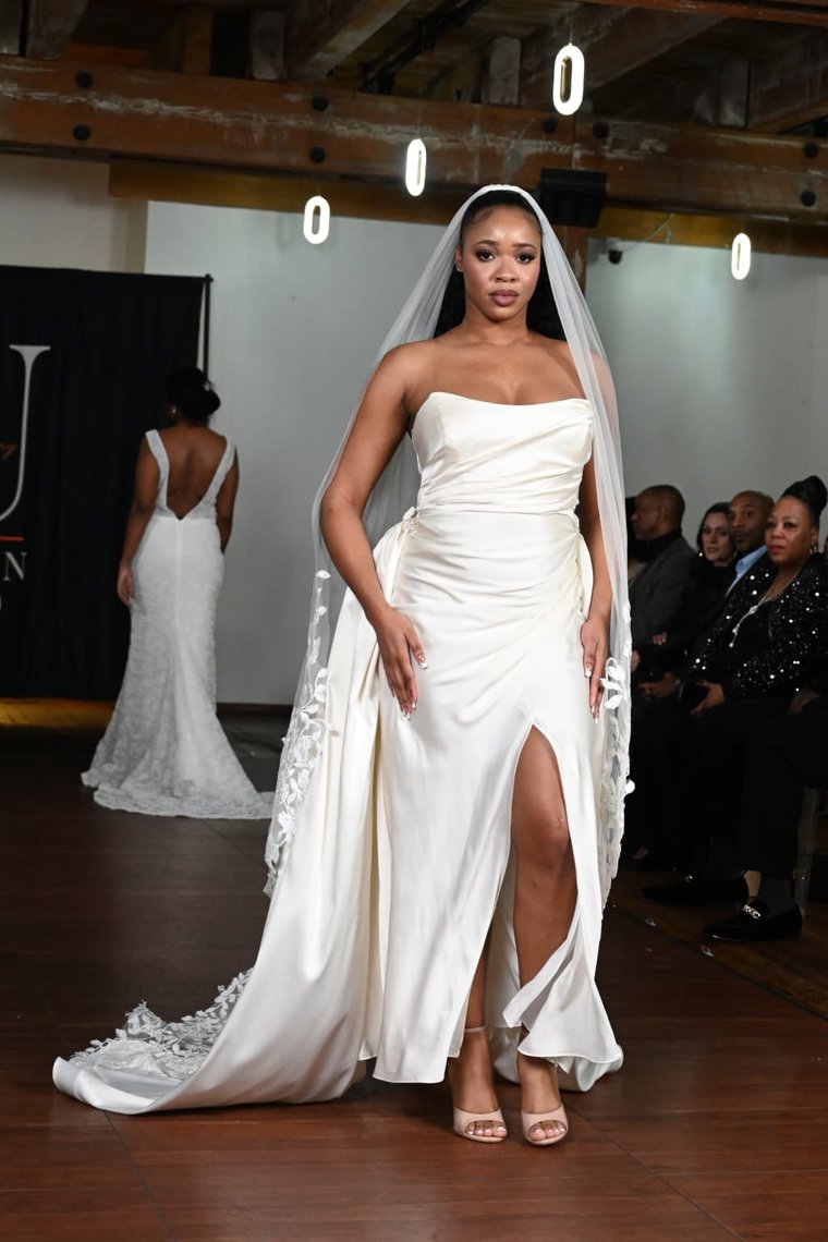 An ivory satin gown with a draped slit skirt and appliquéd veil