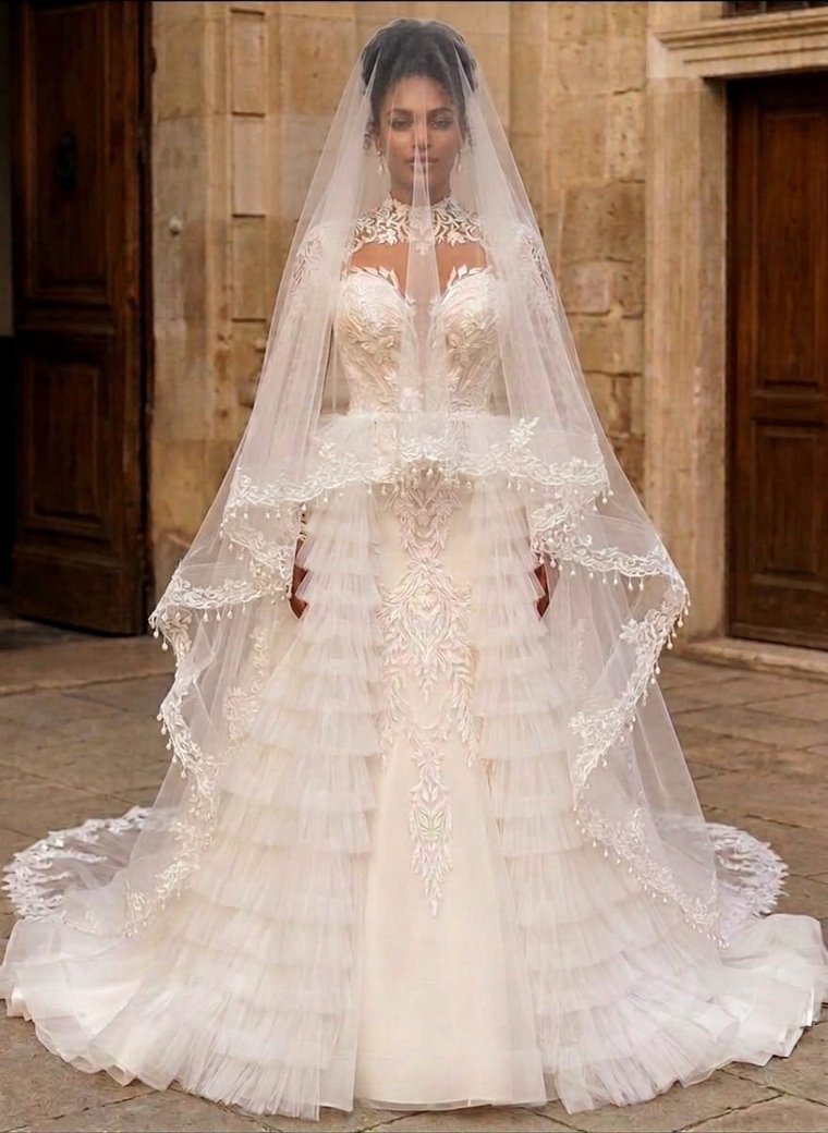 A satin bridal gown with a draped slit skirt and cathedral veil, on the runway